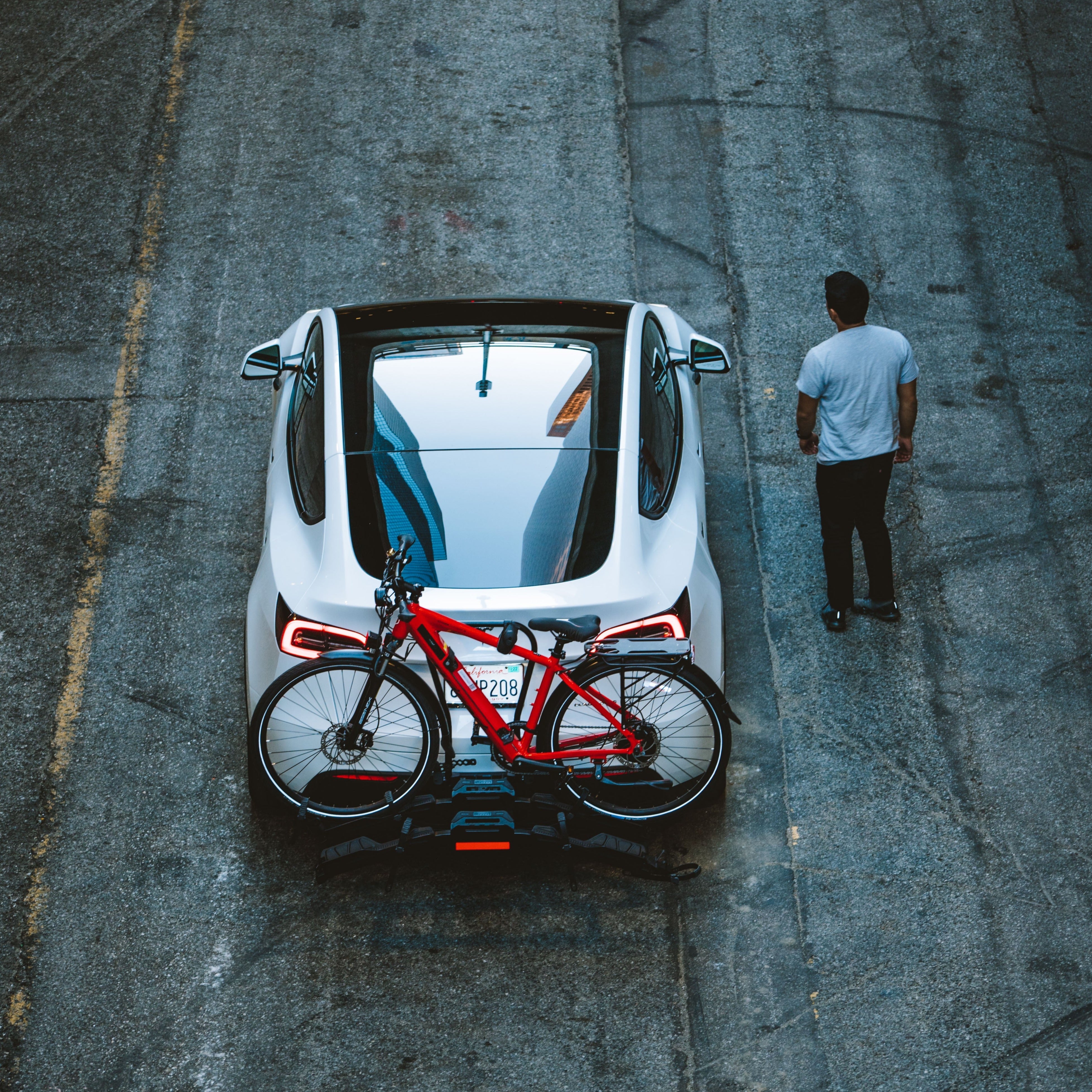 Red electric bike mounted on Destination E rack of white SUV on city street.