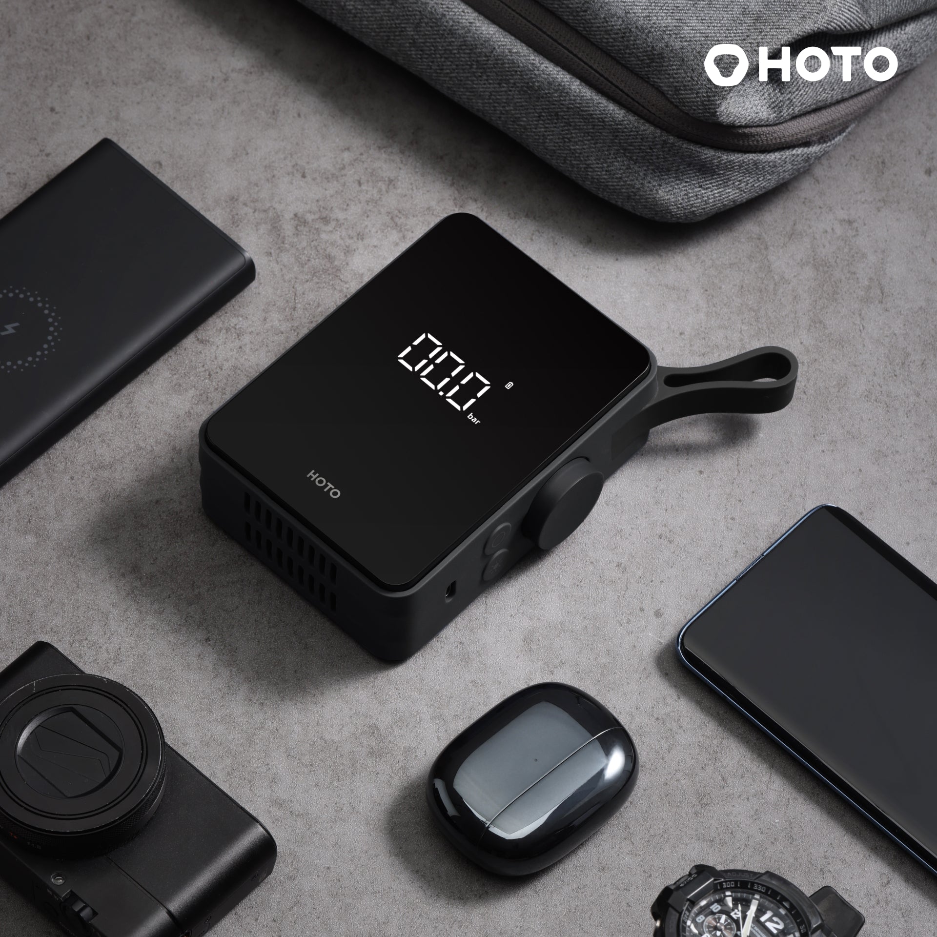 HOTO Electric Air Pump on a surface with digital display, alongside a smartphone and camera.