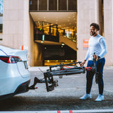 Man holding a folded bike rack while loading it onto a car.