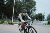 Cyclist wearing Lumos Ultra Fly Pro helmet speeding on a city road.